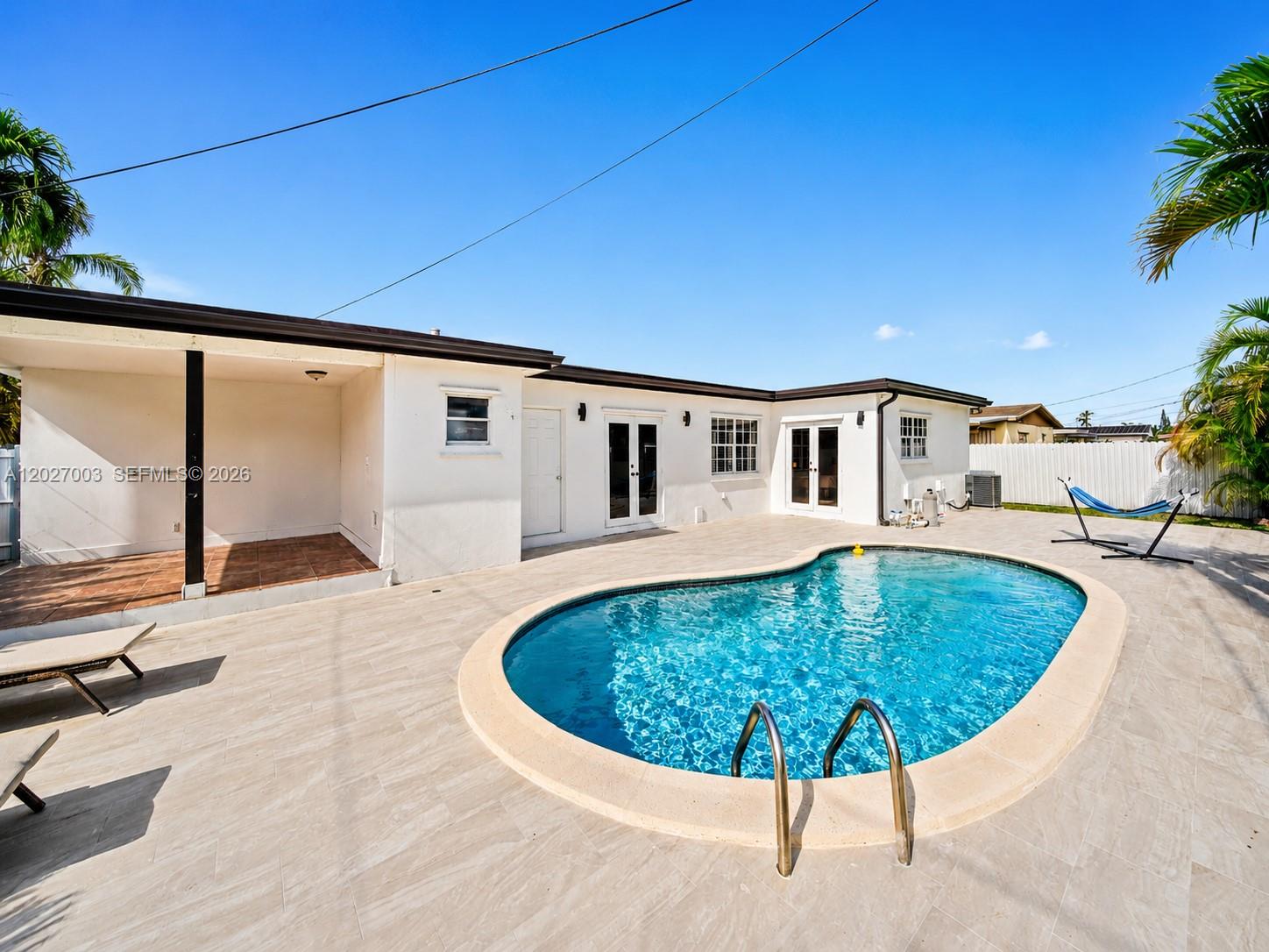 A backyard features a kidney-shaped swimming pool, a covered patio, and a white house exterior — 2761 SW 92nd Pl, Miami FL 33165, MIAMI, FL