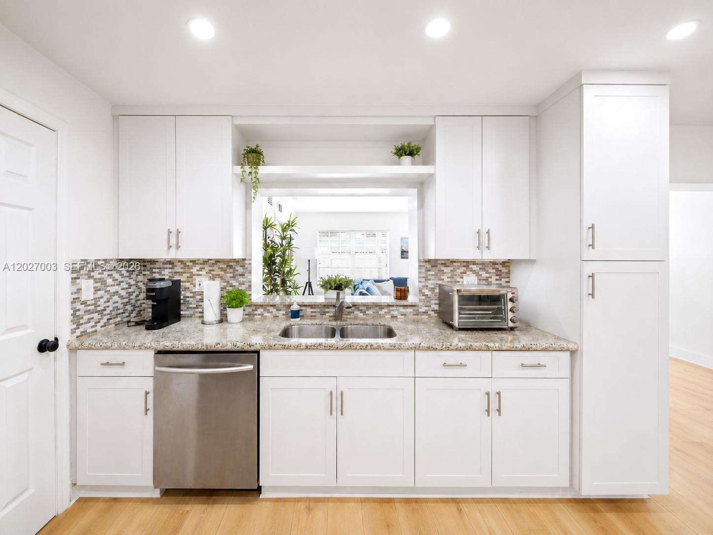 A kitchen features white cabinets, stainless steel appliances, a granite countertop, and a pass-through window — 2761 SW 92nd Pl, Miami FL 33165, MIAMI, FL