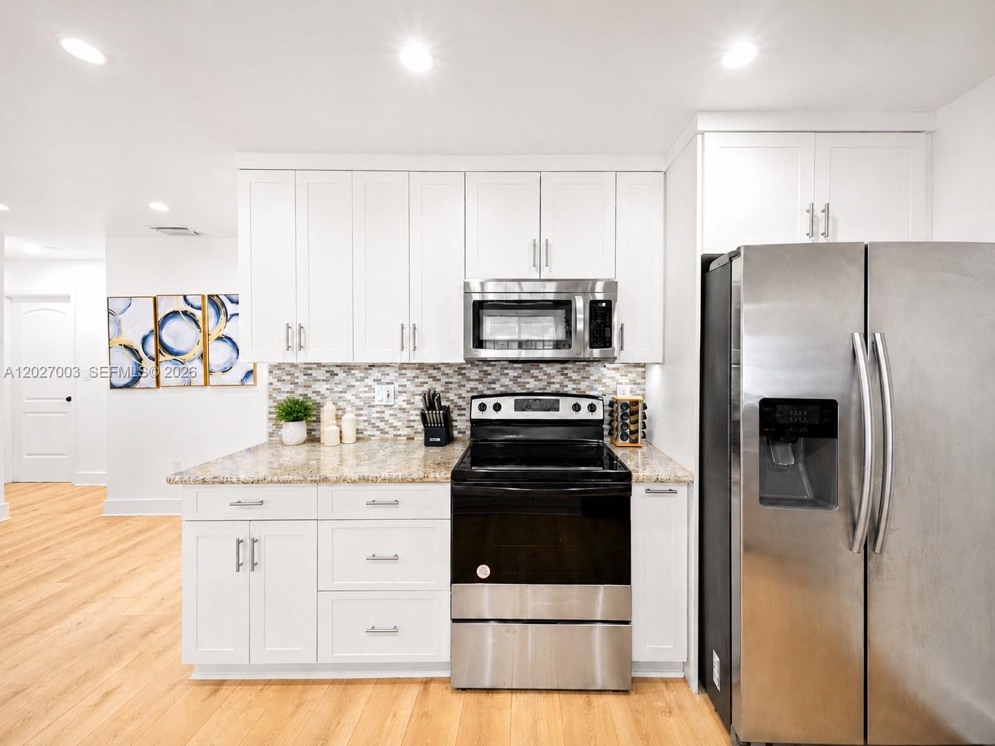 A kitchen features white cabinets, stainless steel appliances, a granite countertop, and a tiled backsplash — 2761 SW 92nd Pl, Miami FL 33165, MIAMI, FL