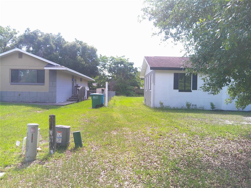 Two houses stand on a grassy lot with utility equipment in the foreground — RIDGEWOOD AVENUE, MAITLAND, FL