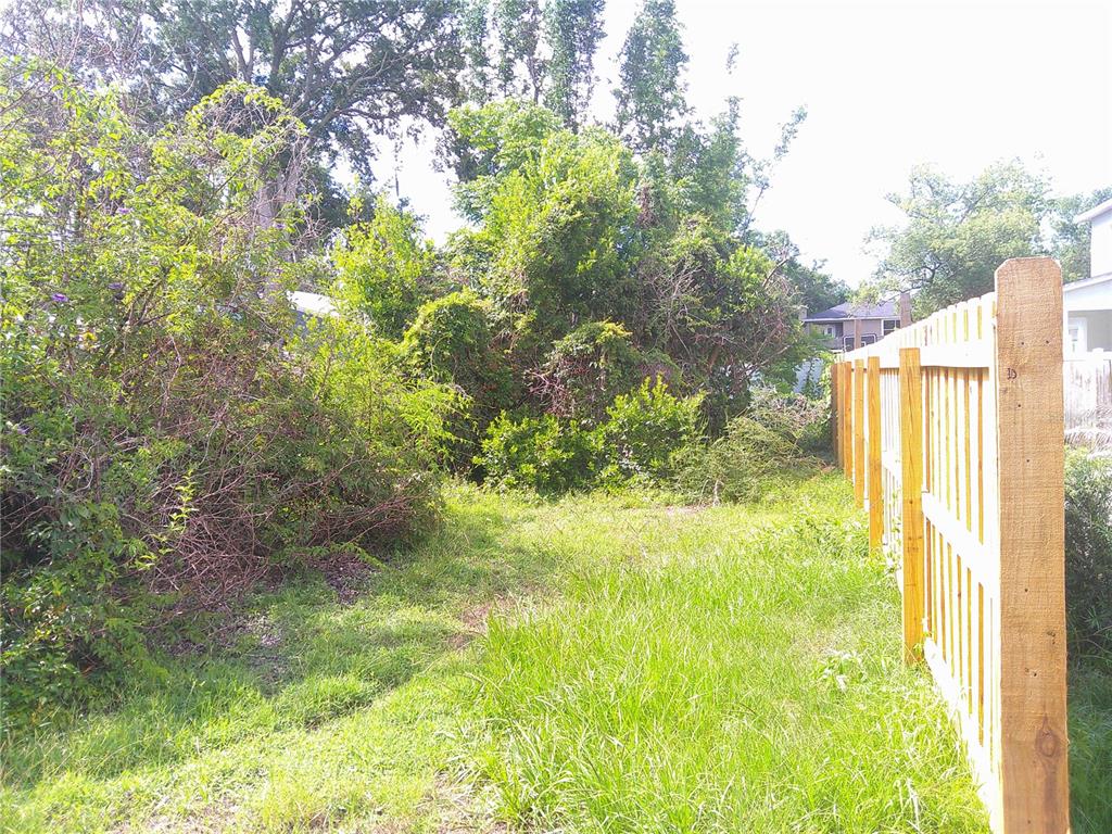 A wooden fence borders a grassy yard with overgrown trees and shrubs — RIDGEWOOD AVENUE, MAITLAND, FL