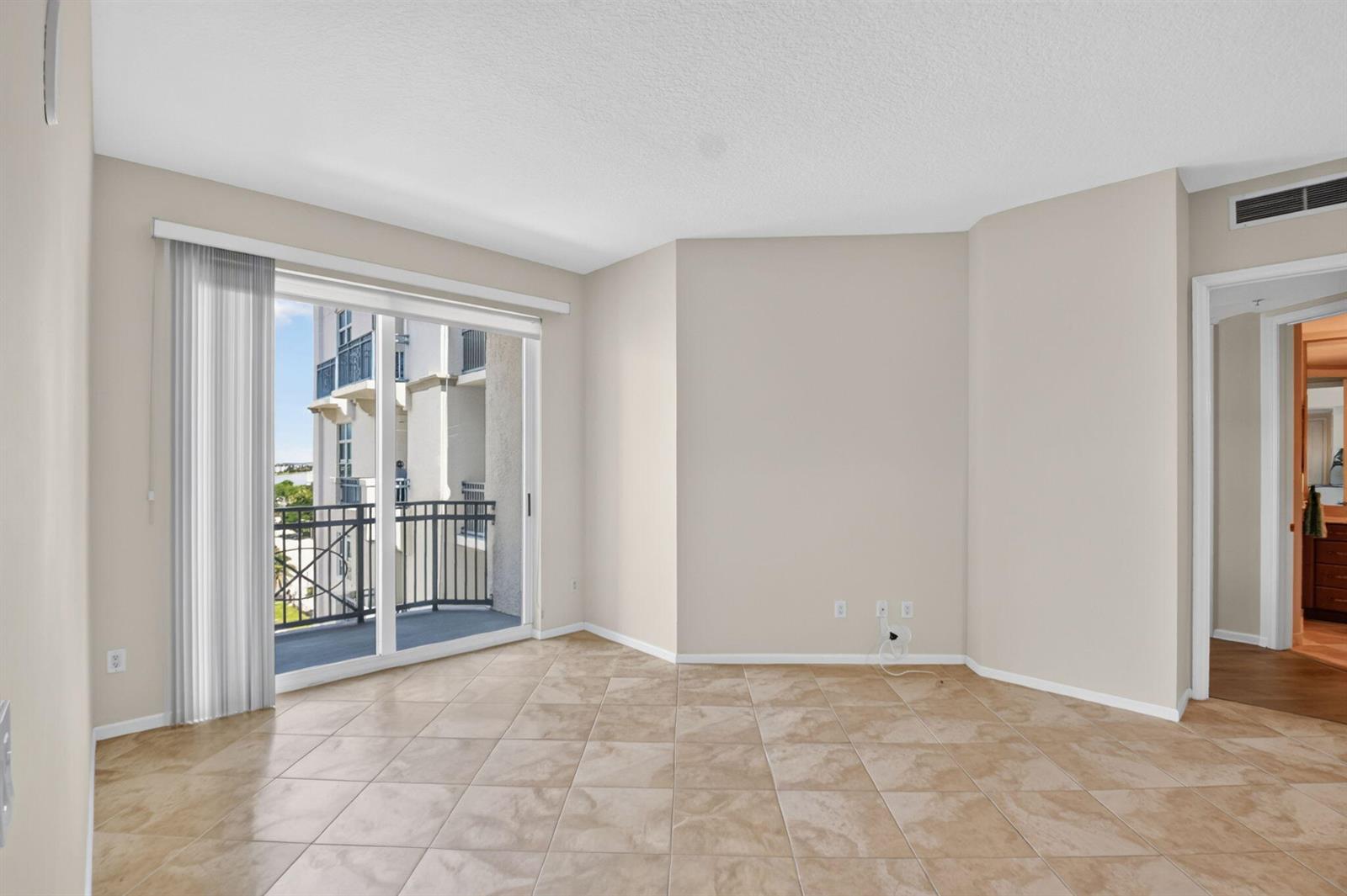 An empty room features beige walls, tile flooring, and a sliding glass door leading to a balcony — 403 S Sapodilla Avenue # 706, West Palm Beach FL 33401, WEST PALM BEACH, FL