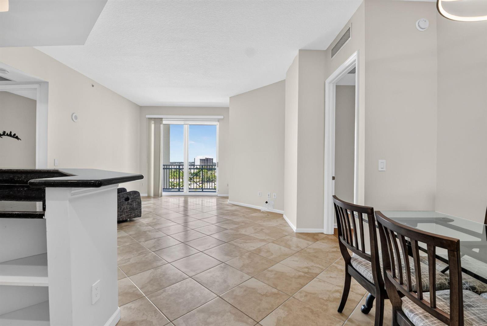 An open-concept living and dining area features tile flooring, a breakfast bar, and balcony access — 403 S Sapodilla Avenue # 706, West Palm Beach FL 33401, WEST PALM BEACH, FL