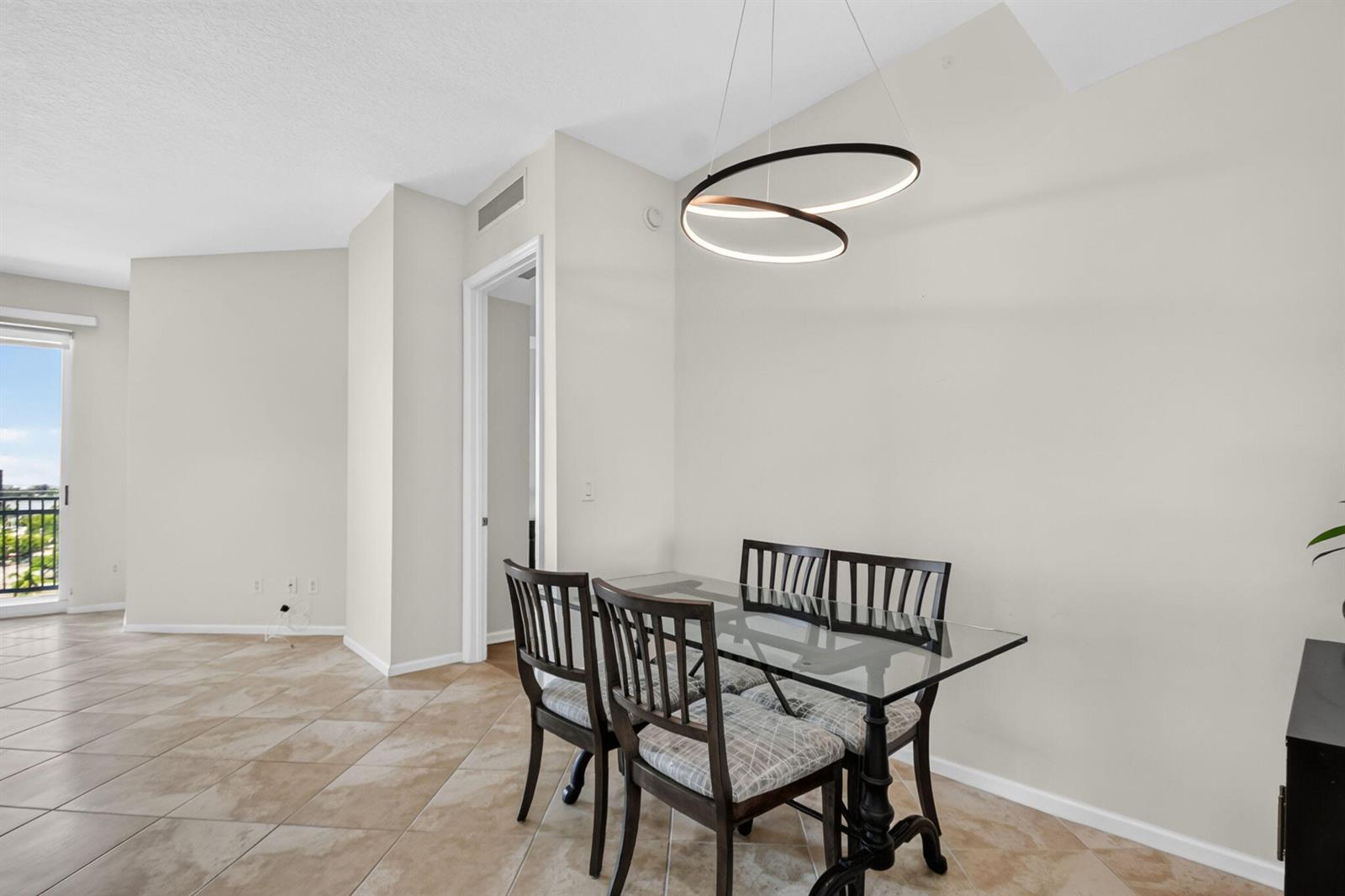 A dining area features a glass-top table, four chairs, and a modern circular pendant light — 403 S Sapodilla Avenue # 706, West Palm Beach FL 33401, WEST PALM BEACH, FL