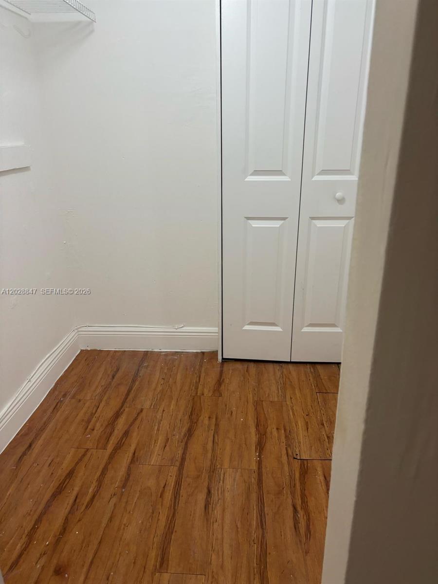 This is a small walk-in closet featuring white walls, wood-look flooring, and a white door — 6675 W 4th Ave # 408, Hialeah FL 33012, HIALEAH, FL
