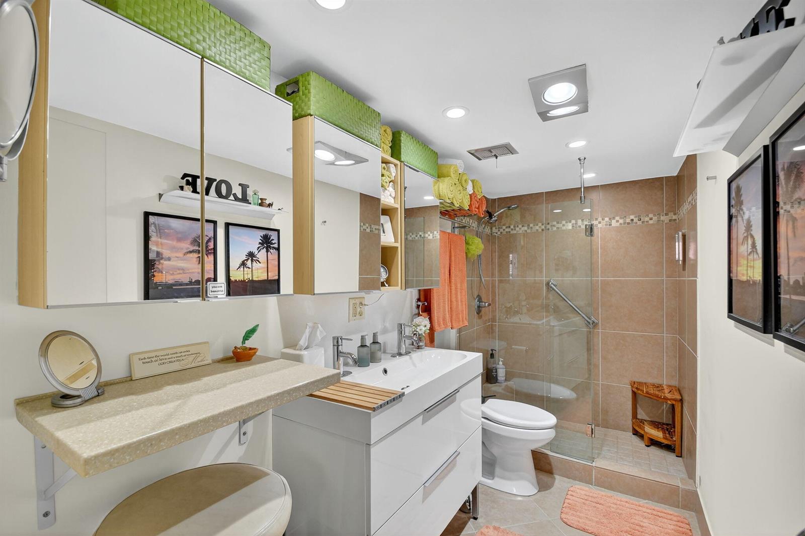 A bathroom features a double vanity, a glass-enclosed shower, and a wall-mounted makeup counter — 7 Golfs Edge # D, West Palm Beach FL 33417, WEST PALM BEACH, FL
