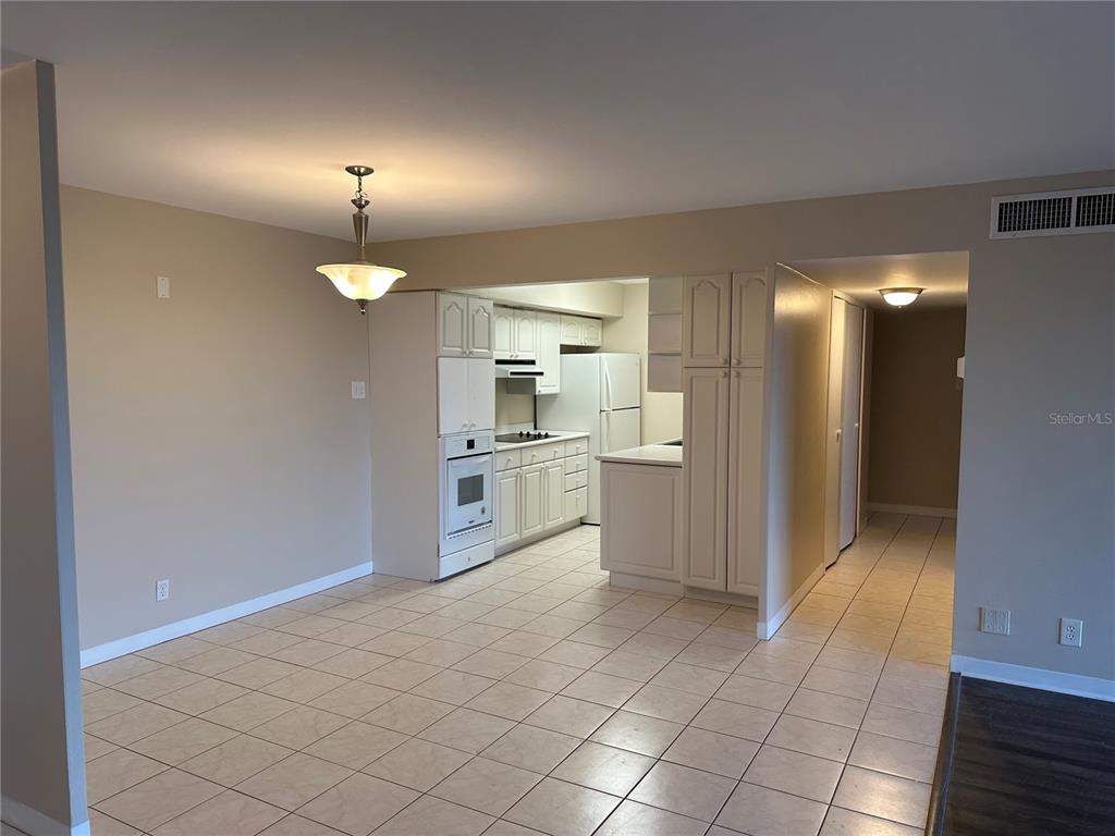 A kitchen with white cabinets and tile flooring opens into a dining area — 10355 PARADISE BOULEVARD UNIT 414, TREASURE ISLAND, FL