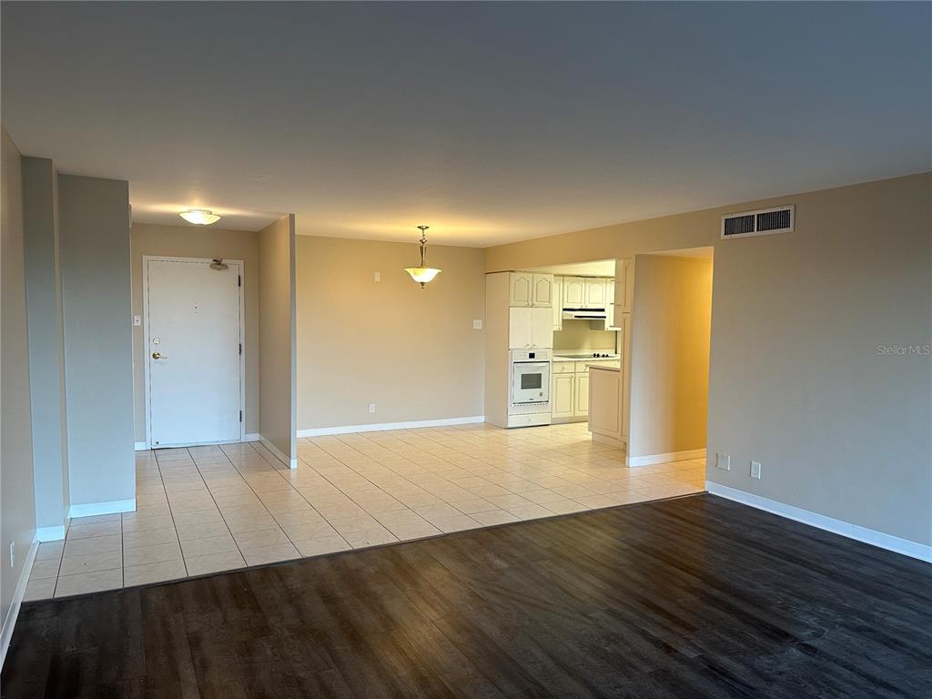 An open-concept living area features tile flooring near the entrance and dark wood-look flooring elsewhere — 10355 PARADISE BOULEVARD UNIT 414, TREASURE ISLAND, FL