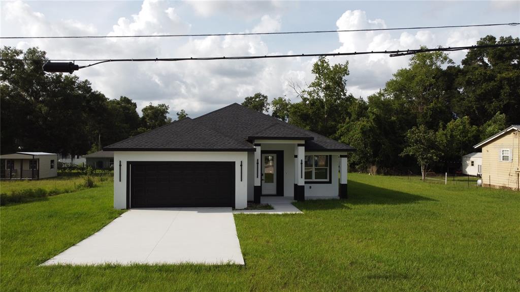 A newly constructed single-story house with a white exterior, black roof, and attached garage — 3649 SE 142ND STREET, SUMMERFIELD, FL