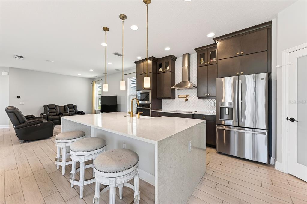 A modern kitchen features a large quartz island, dark wood cabinetry, and stainless steel appliances — 640 DOGFISH LANE, DEBARY, FL