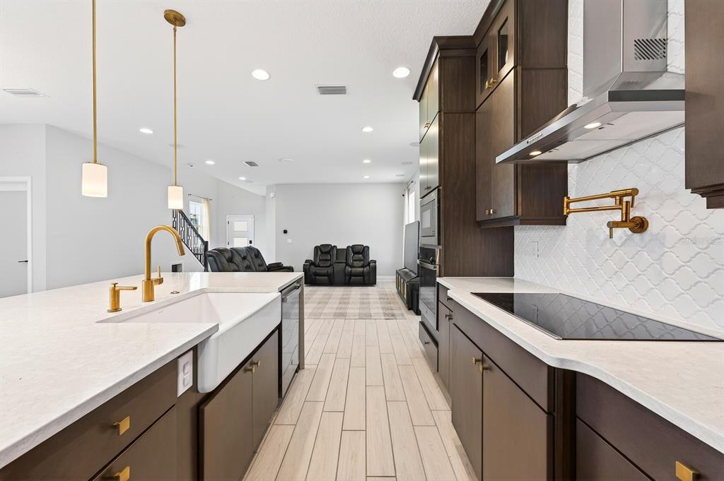 A modern kitchen features dark wood cabinets, white countertops, a farmhouse sink, and gold fixtures — 640 DOGFISH LANE, DEBARY, FL