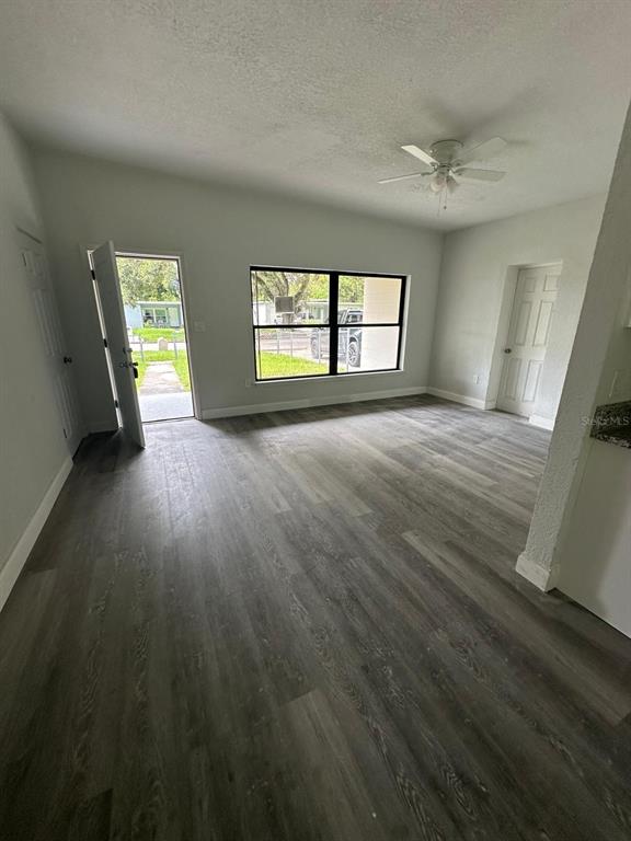 An interior view shows a living area with gray wood-look flooring and a ceiling fan — 4514 ARCH STREET, ORLANDO, FL