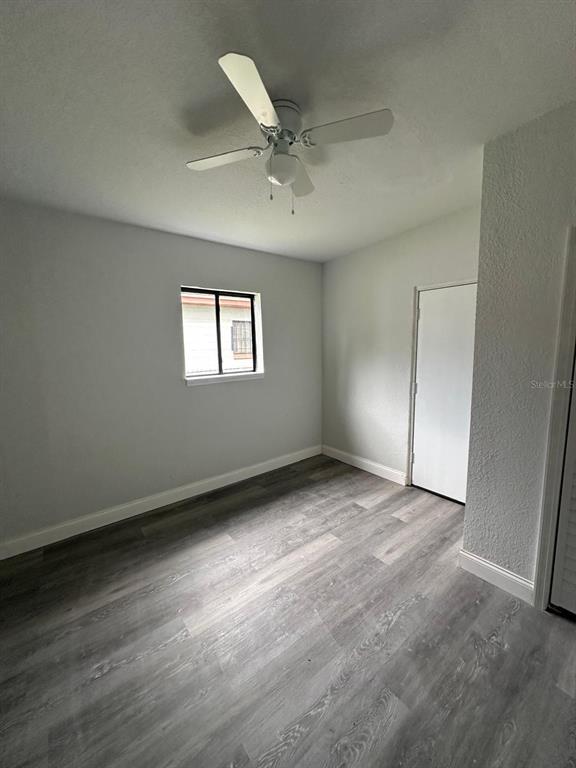 A bedroom with light gray walls, wood-look flooring, a ceiling fan, and a single window — 4514 ARCH STREET, ORLANDO, FL