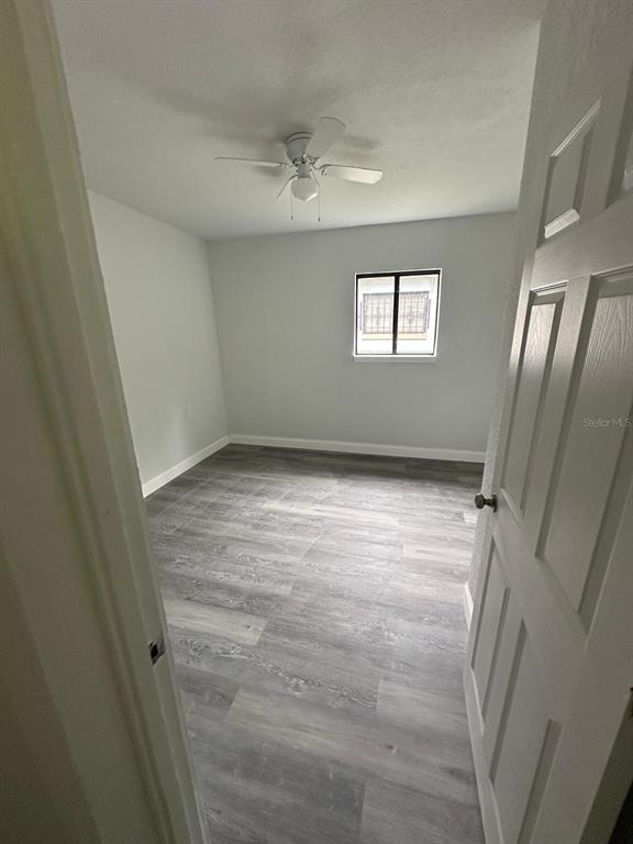 An empty bedroom features gray wood-look flooring, a ceiling fan, and a single window — 4514 ARCH STREET, ORLANDO, FL