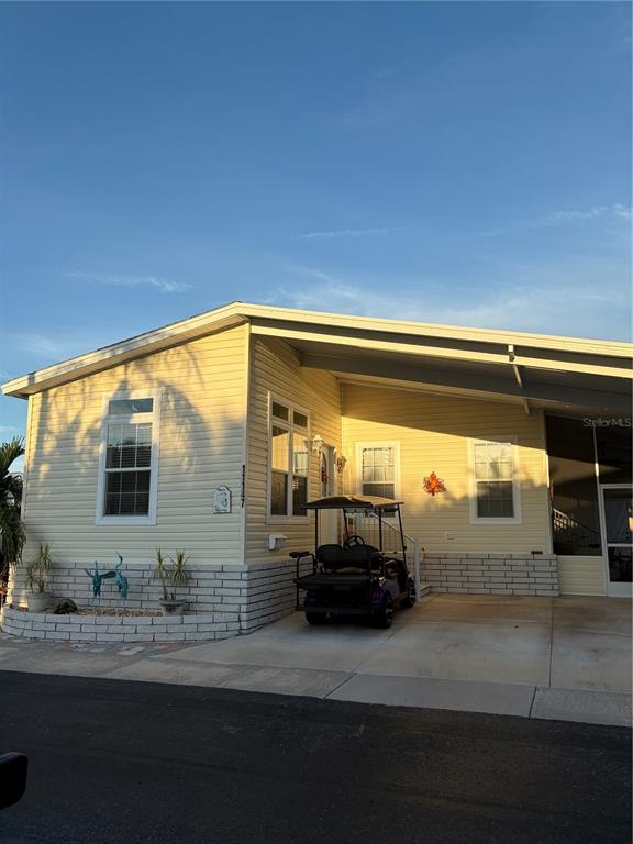 A yellow mobile home with a carport and a golf cart parked in the driveway — 11147 102ND WAY UNIT 212, LARGO, FL