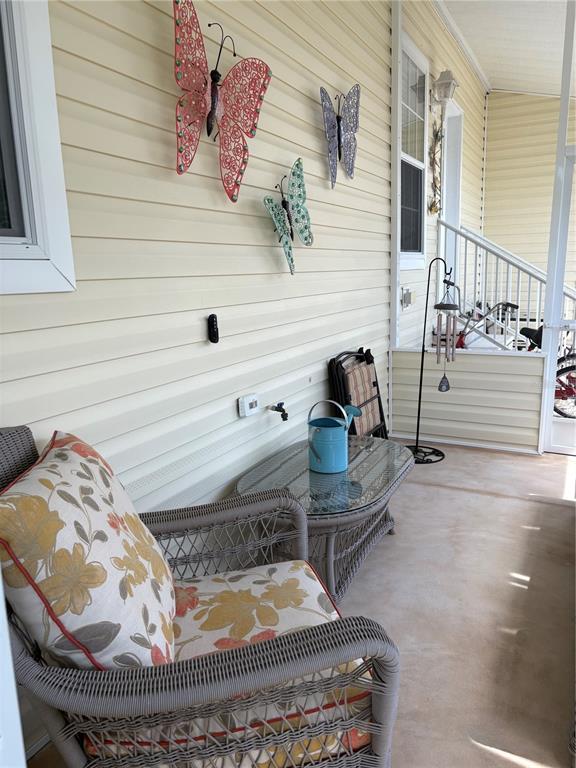 A covered porch features wicker furniture, a glass-top table, and decorative butterfly wall art — 11147 102ND WAY UNIT 212, LARGO, FL