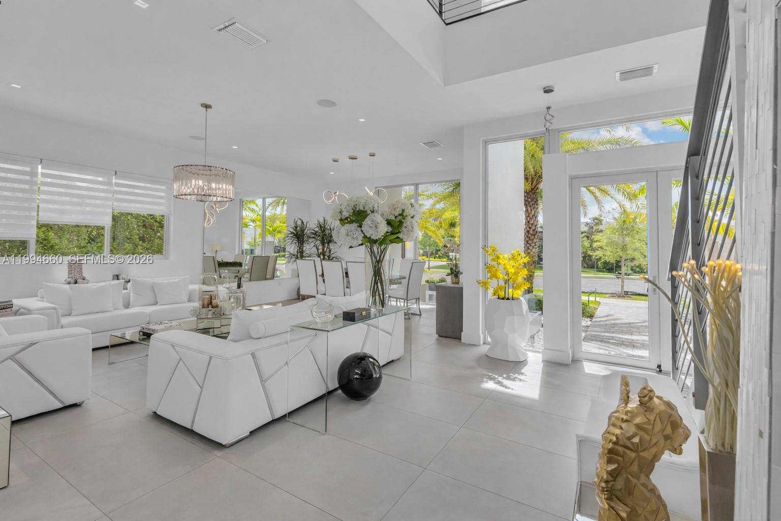A bright, modern living room features white furniture, tile floors, and large windows — 16631 Sunset Way, Weston FL 33326, WESTON, FL