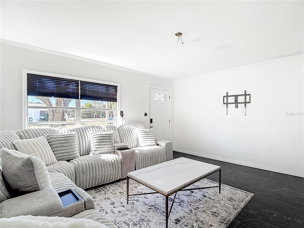 A living room features a grey sectional sofa, a marble coffee table, and dark flooring — 6726 DEL PRADO TERRACE, NEW PORT RICHEY, FL
