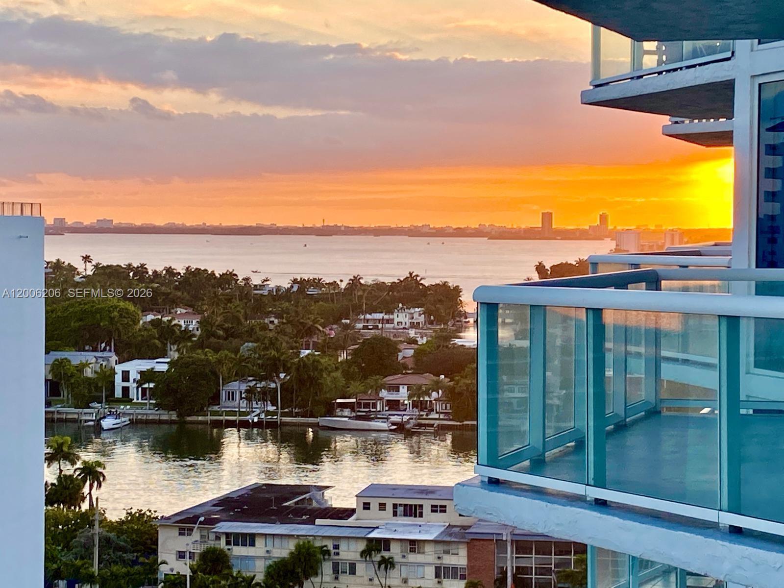 A high-angle view of a sunset over a bay with residential buildings and balconies — 6515 Collins Ave # 1505, Miami Beach FL 33141, MIAMI BEACH, FL