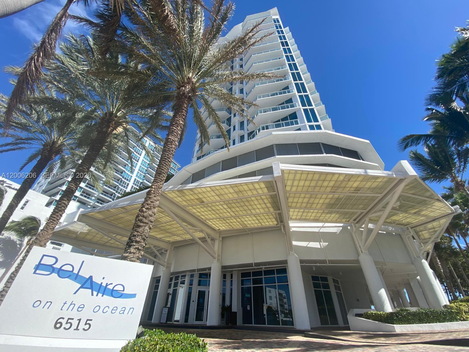 A tall residential building with a large canopy entrance and palm trees under blue sky — 6515 Collins Ave # 1505, Miami Beach FL 33141, MIAMI BEACH, FL