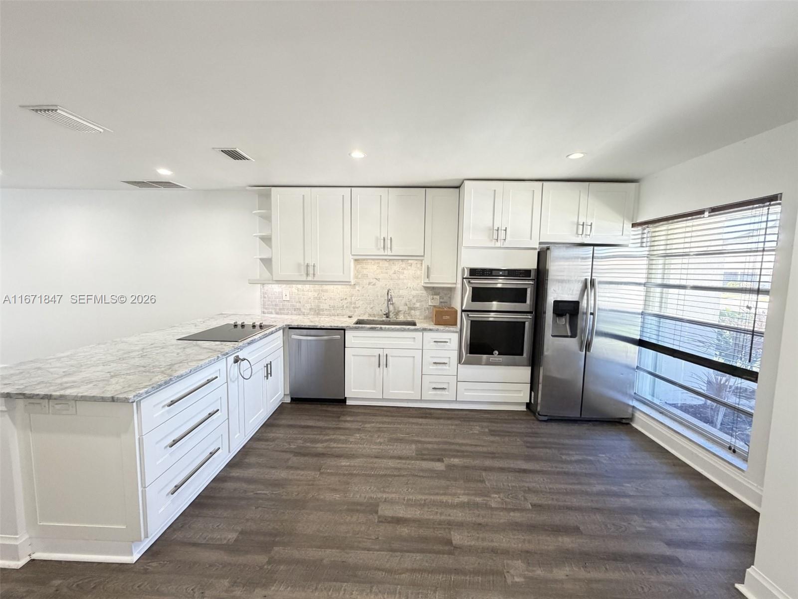 A modern kitchen features white cabinets, stainless steel appliances, and a marble-patterned countertop island — 20927 Sedgewick Dr, Boca Raton FL 33433, BOCA RATON, FL