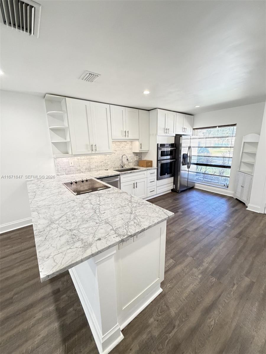 A kitchen features white cabinets, a marble-patterned island countertop, and dark wood-look flooring — 20927 Sedgewick Dr, Boca Raton FL 33433, BOCA RATON, FL