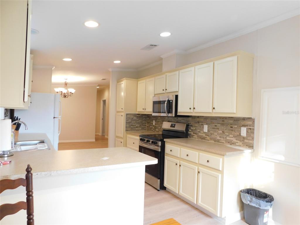 A kitchen features cream-colored cabinets, stainless steel appliances, and a tiled backsplash — 200 COLUMBIA STREET, ARCADIA, FL