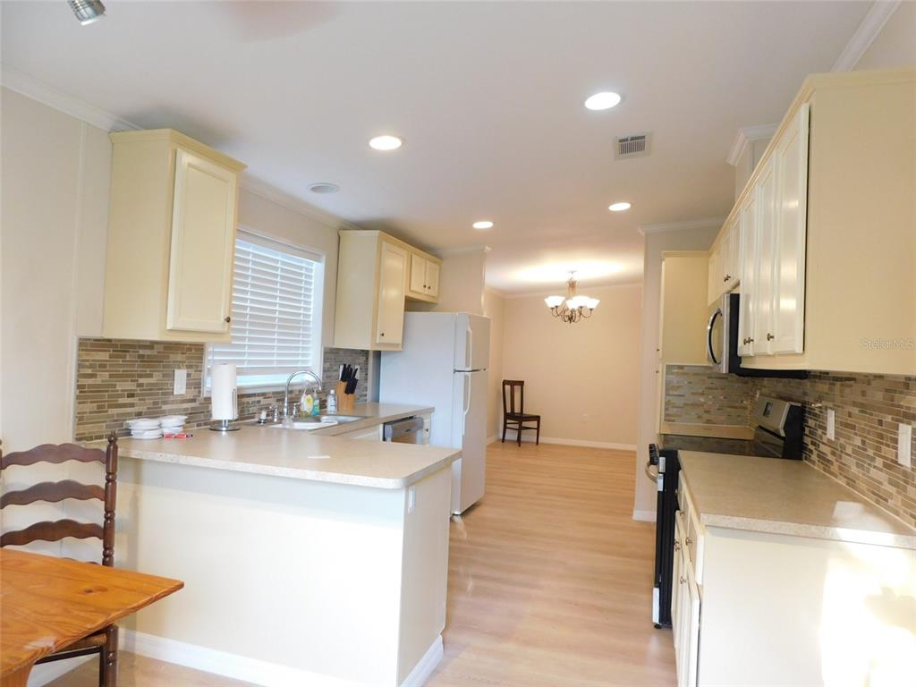 A kitchen with light-colored cabinets, a breakfast bar, and a dining area in the background — 200 COLUMBIA STREET, ARCADIA, FL