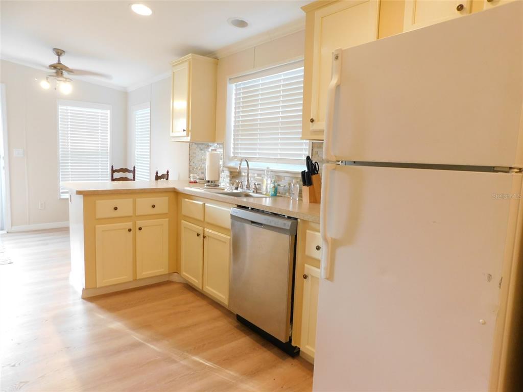 A kitchen features light-colored cabinets, a stainless steel dishwasher, and a white refrigerator — 200 COLUMBIA STREET, ARCADIA, FL