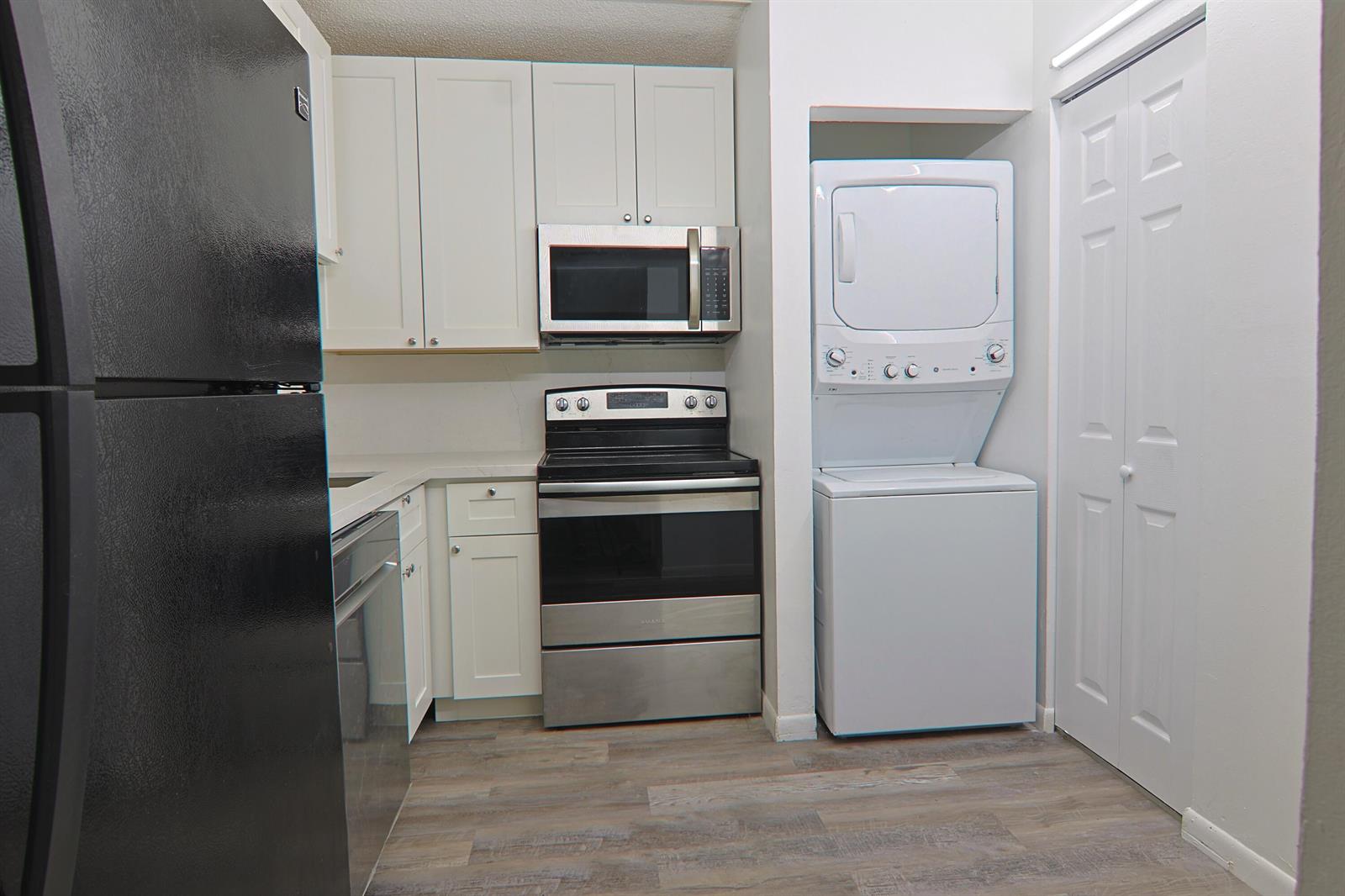 A kitchen features white cabinets, stainless steel appliances, and a stacked washer and dryer unit — 6931 SW 129th Avenue # 3, Miami FL 33183, MIAMI, FL