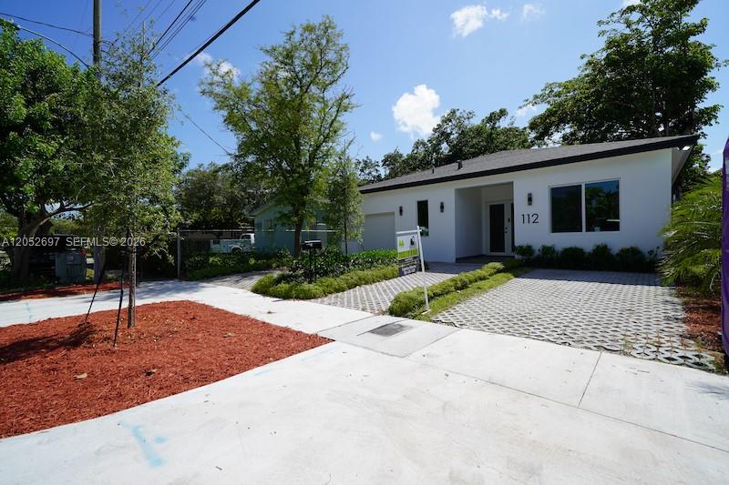 A white single-story house features a paved driveway and a landscaped front yard — 112 NW 24th Ct, Miami FL 33125, MIAMI, FL
