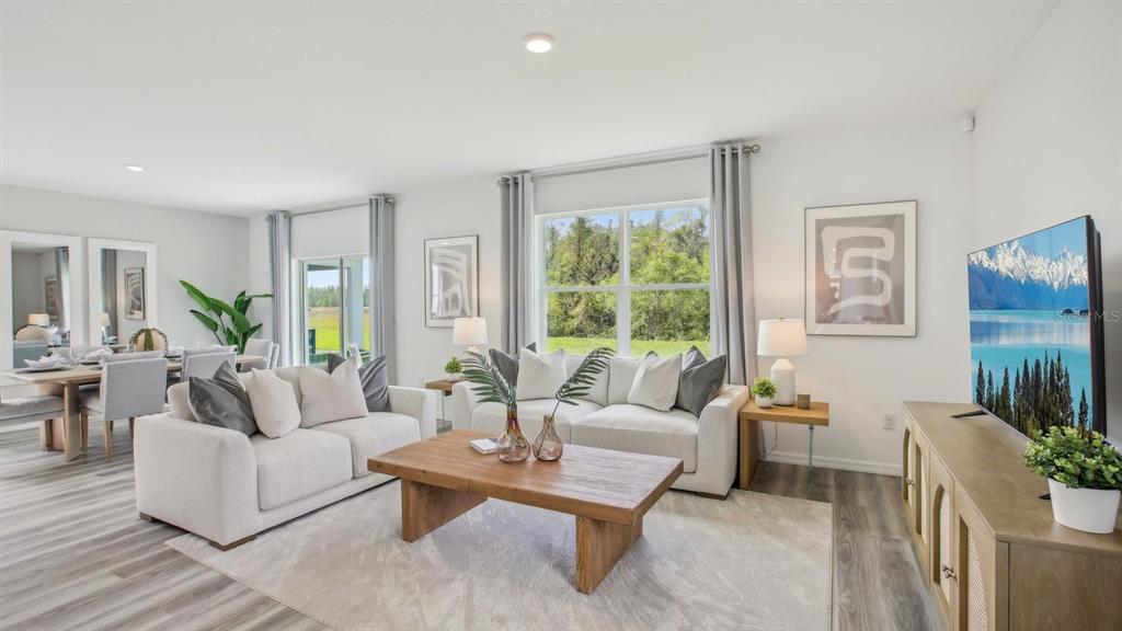 A bright living room features a wooden coffee table, two sofas, and a television — 7088 FLINT CREEK DRIVE, LAND O LAKES, FL