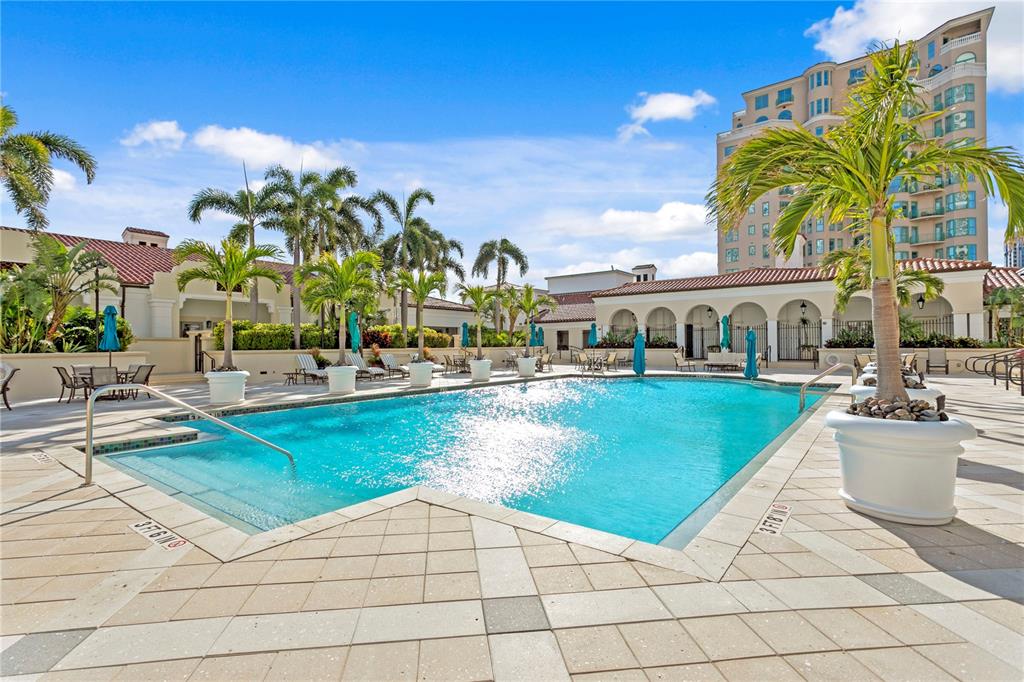 A swimming pool with palm trees and a tall building in the background — 300 BEACH DRIVE NE UNIT 1201, ST PETERSBURG, FL