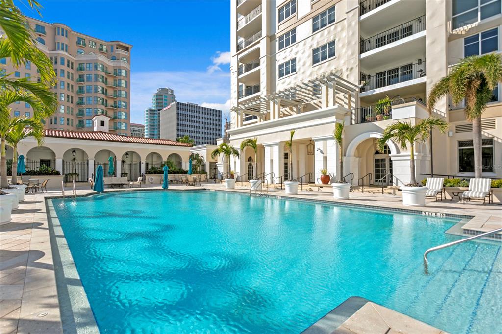 A large outdoor swimming pool sits in front of a multi-story apartment building with balconies — 300 BEACH DRIVE NE UNIT 1201, ST PETERSBURG, FL