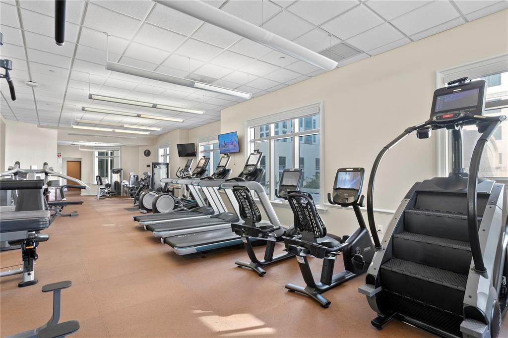 A fitness center features multiple treadmills, stationary bikes, and a stair climber on brown flooring — 300 BEACH DRIVE NE UNIT 1201, ST PETERSBURG, FL