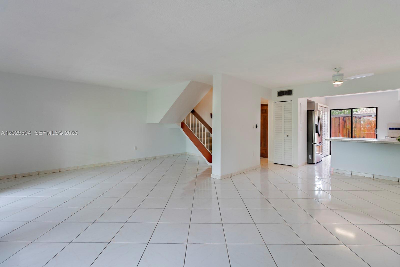 An open-concept living area features white tile flooring, a staircase, and an adjacent kitchen — 3804 SW 79th Ave # 76, Miami FL 33155, MIAMI, FL