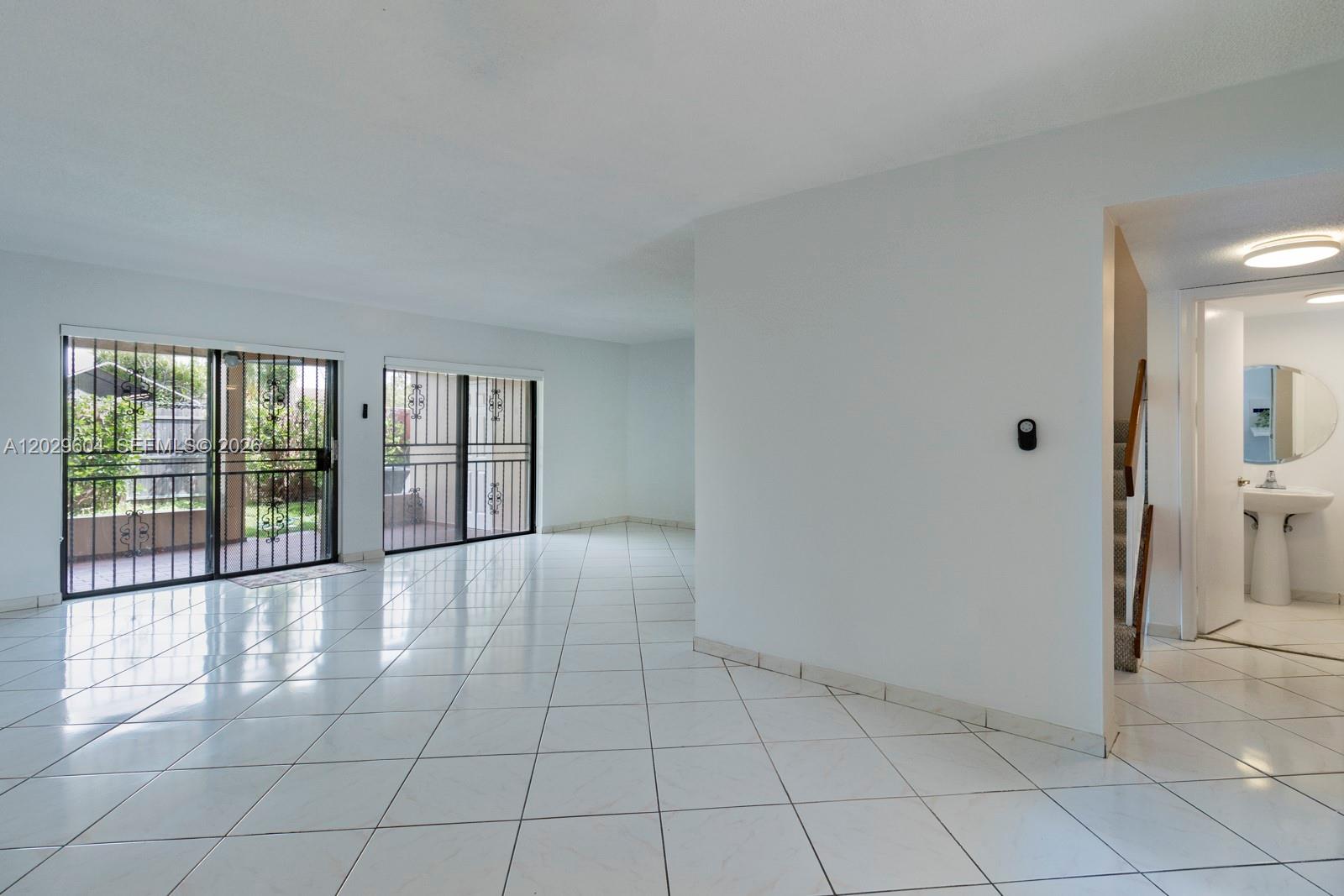 A bright living area features white tile floors, sliding glass doors, and an adjacent bathroom — 3804 SW 79th Ave # 76, Miami FL 33155, MIAMI, FL