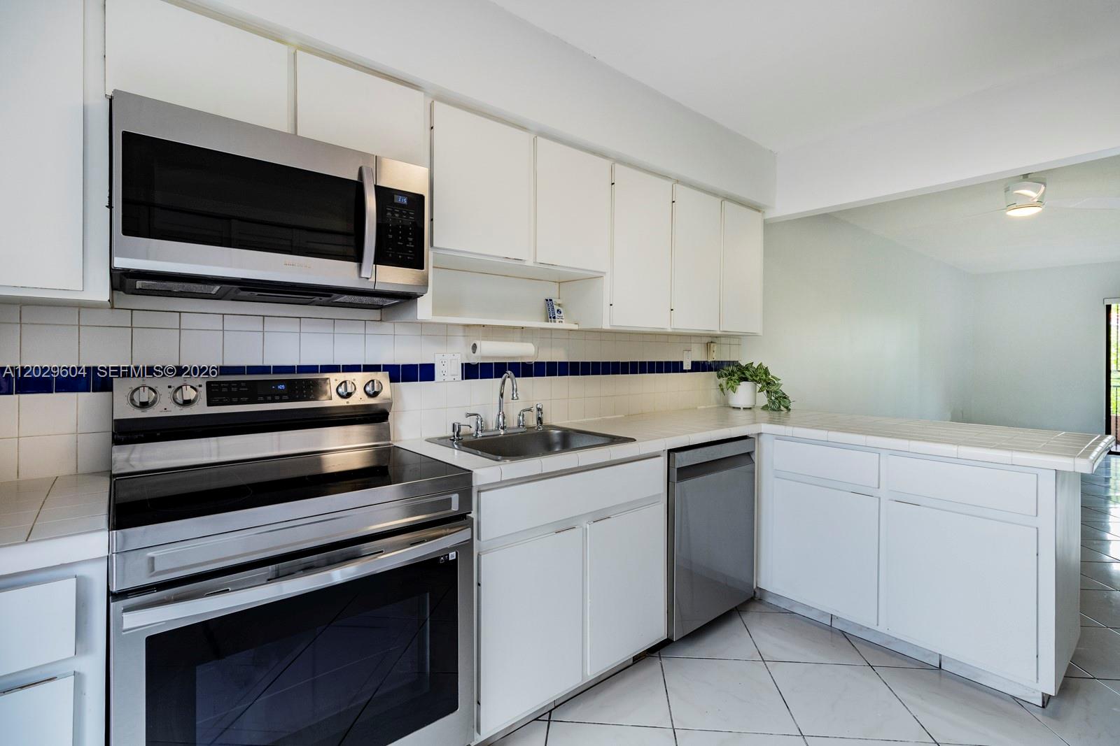 A kitchen features white cabinets, stainless steel appliances, tiled countertops, and a blue backsplash — 3804 SW 79th Ave # 76, Miami FL 33155, MIAMI, FL