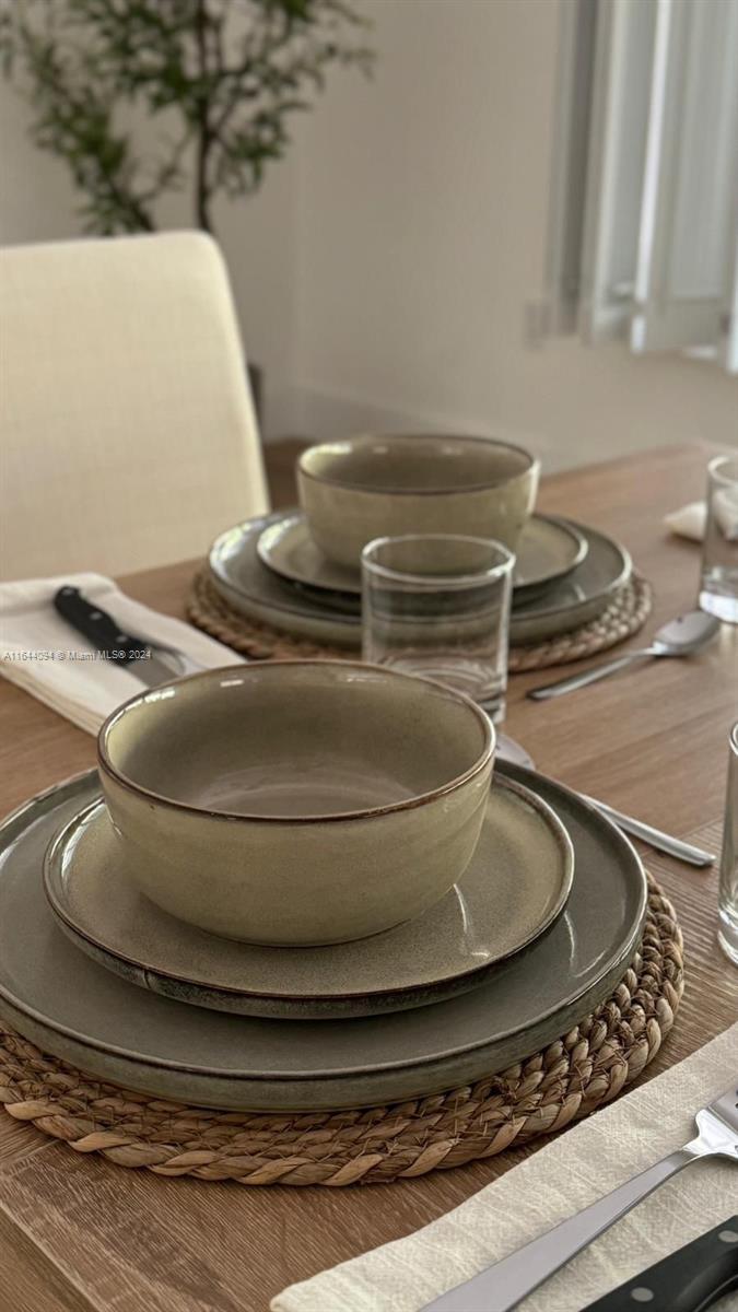 A dining table is set with stoneware bowls and plates on woven placemats — 630 NE 117th St, Biscayne Park FL 33161, BISCAYNE PARK, FL