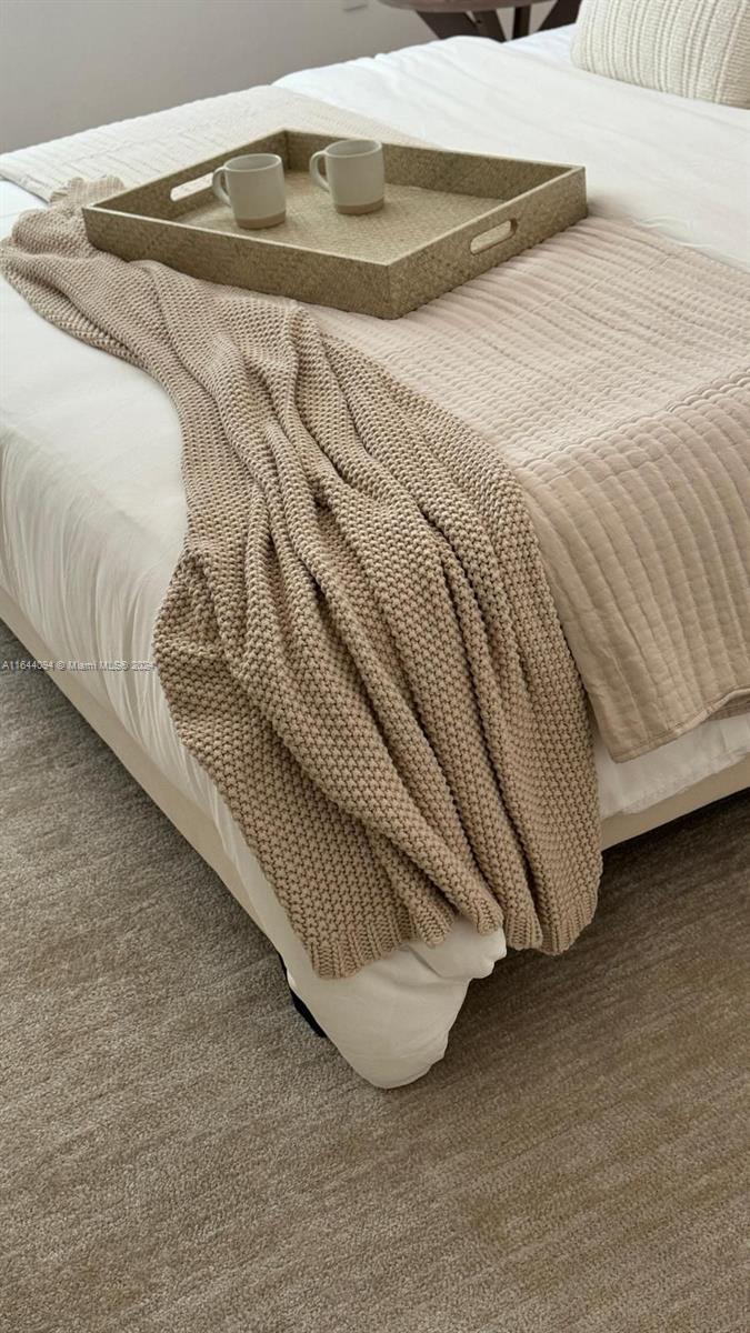 A beige knit throw blanket and a tray with two mugs rest on a bed — 630 NE 117th St, Biscayne Park FL 33161, BISCAYNE PARK, FL