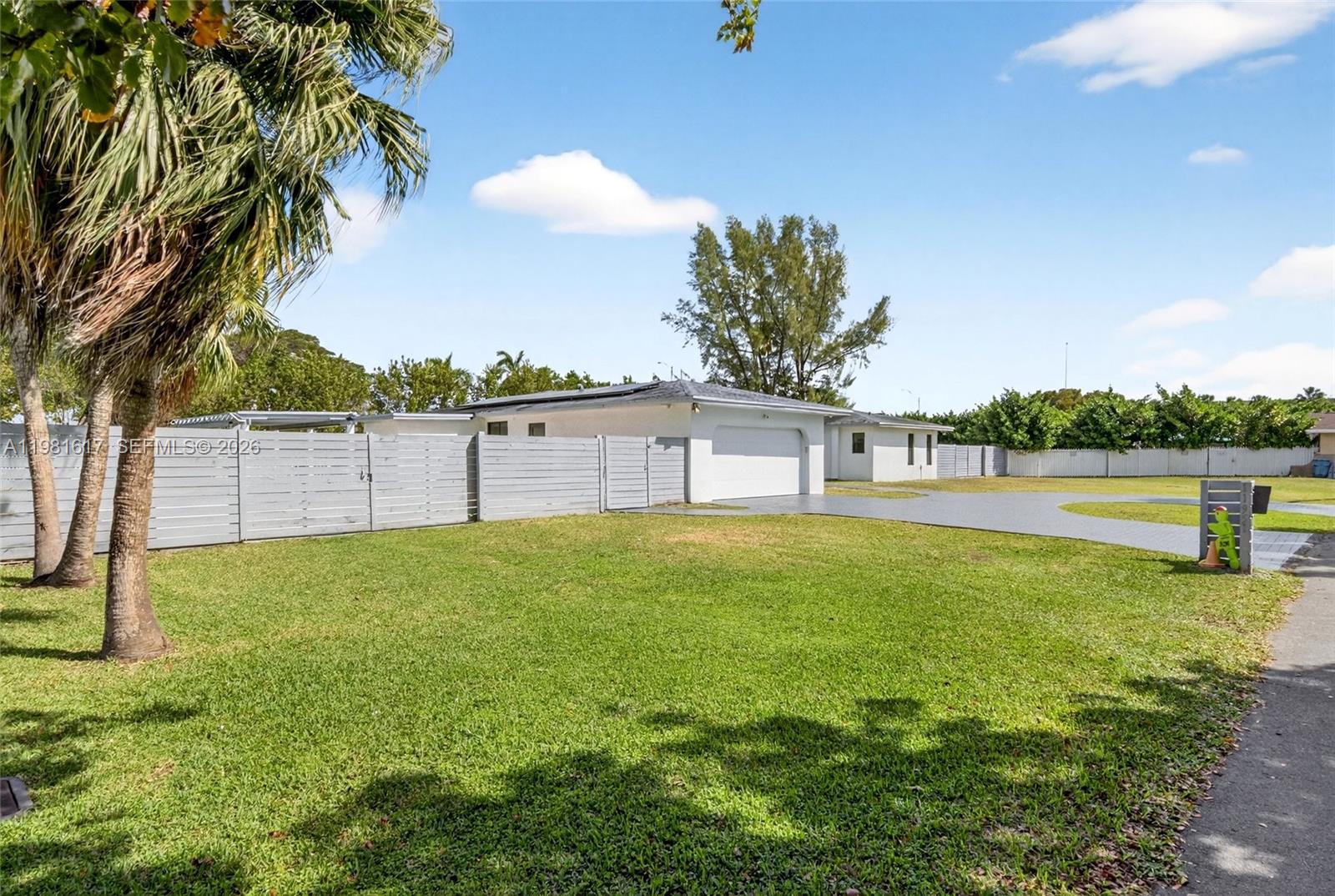 A white house with a garage and a large lawn sits behind a gray fence — 11951 SW 120th Ter, Miami FL 33186, MIAMI, FL