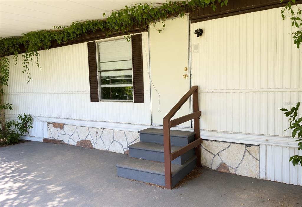 A white mobile home exterior features a window with brown shutters and gray wooden steps — 9136 SW 31ST AVENUE ROAD, OCALA, FL