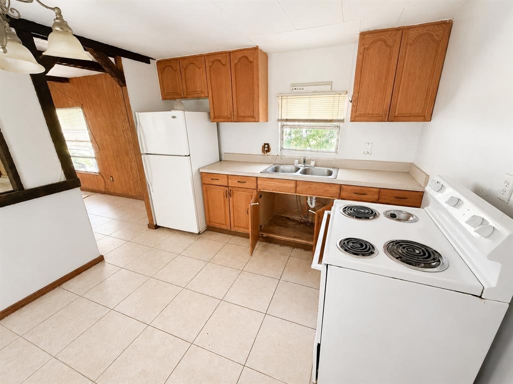 A kitchen features wood cabinets, a white refrigerator, a white electric stove, and tile flooring — 9136 SW 31ST AVENUE ROAD, OCALA, FL