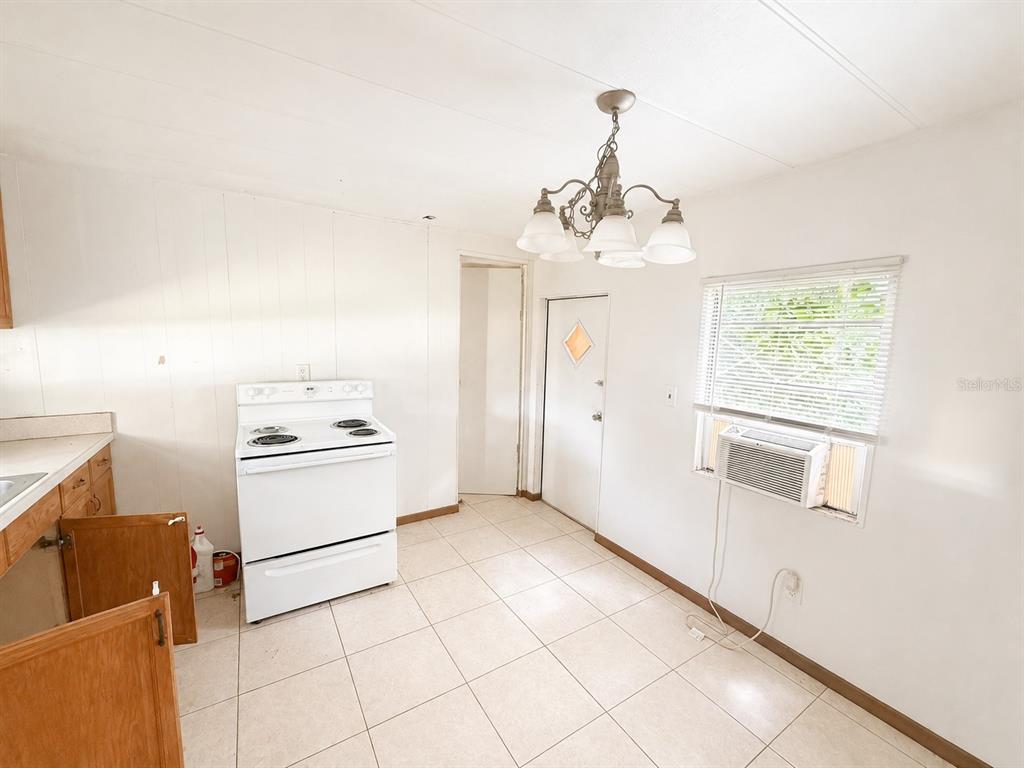 A kitchen with white walls, tile flooring, a white stove, and a window air conditioner — 9136 SW 31ST AVENUE ROAD, OCALA, FL