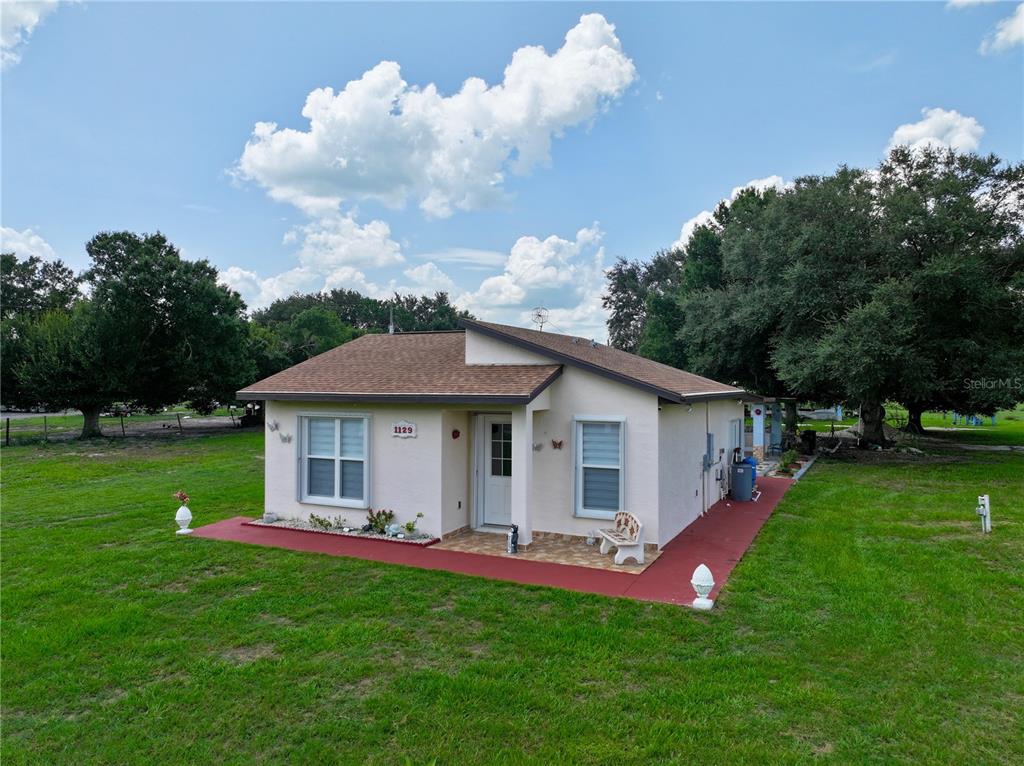 A single-story house with a red concrete walkway sits on a grassy lot — 1129 HOPKINS LANE, ZOLFO SPRINGS, FL