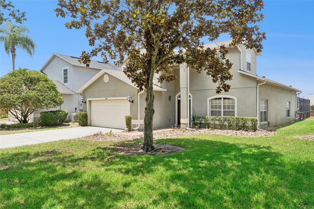 A two-story house with a beige stucco exterior, a two-car garage, and a front lawn — 8007 ACADIA ESTATES COURT, KISSIMMEE, FL