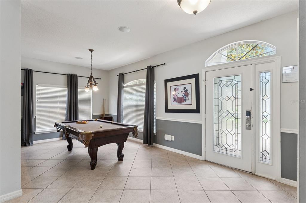 A room with tile floors, gray wainscoting, and a pool table near the front entrance — 8007 ACADIA ESTATES COURT, KISSIMMEE, FL