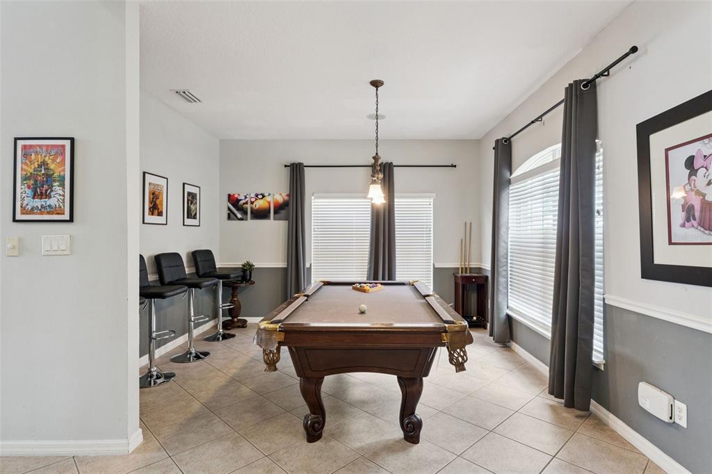 A game room features a pool table, bar stools, and two windows with gray curtains — 8007 ACADIA ESTATES COURT, KISSIMMEE, FL