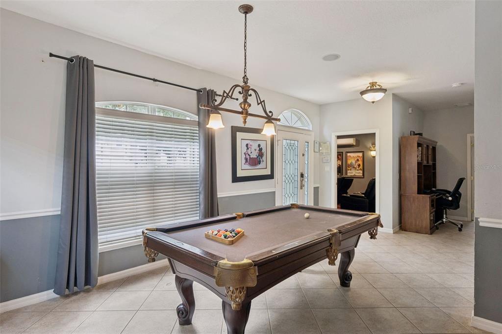 A game room features a pool table, tile flooring, and a chandelier under a tray ceiling — 8007 ACADIA ESTATES COURT, KISSIMMEE, FL