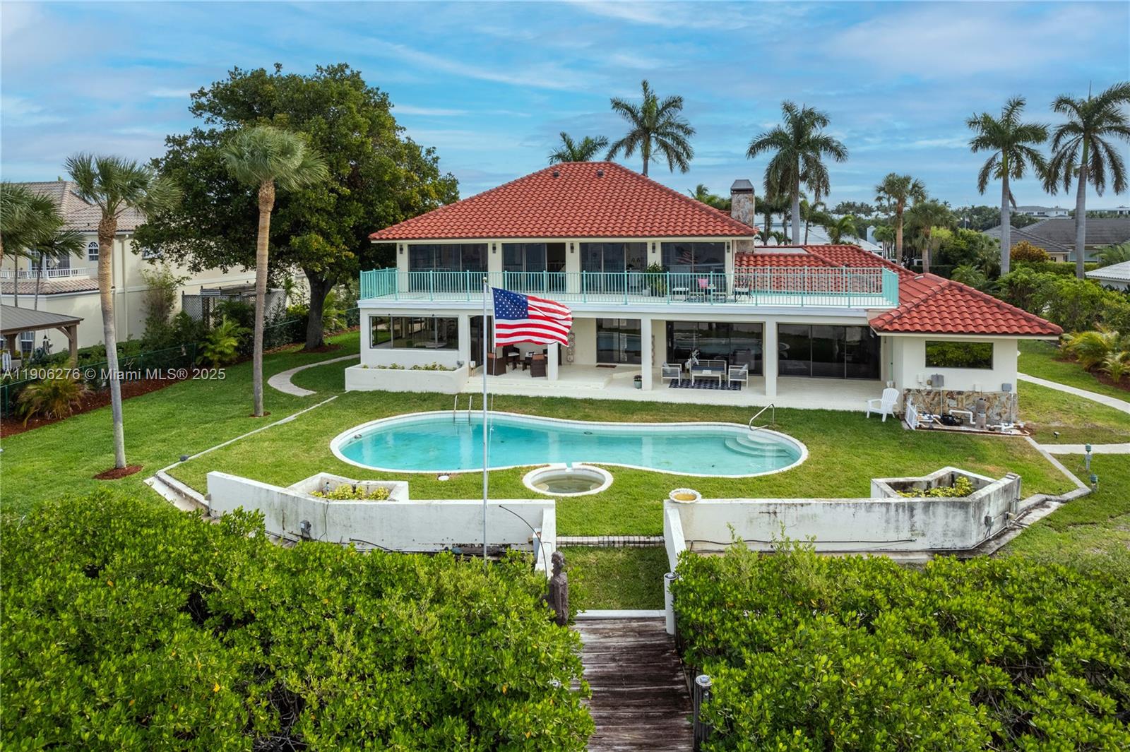 A two-story house with a red tile roof, swimming pool, and American flag in backyard — 1635 Lands End Rd, Manalapan FL 33462, MANALAPAN, FL